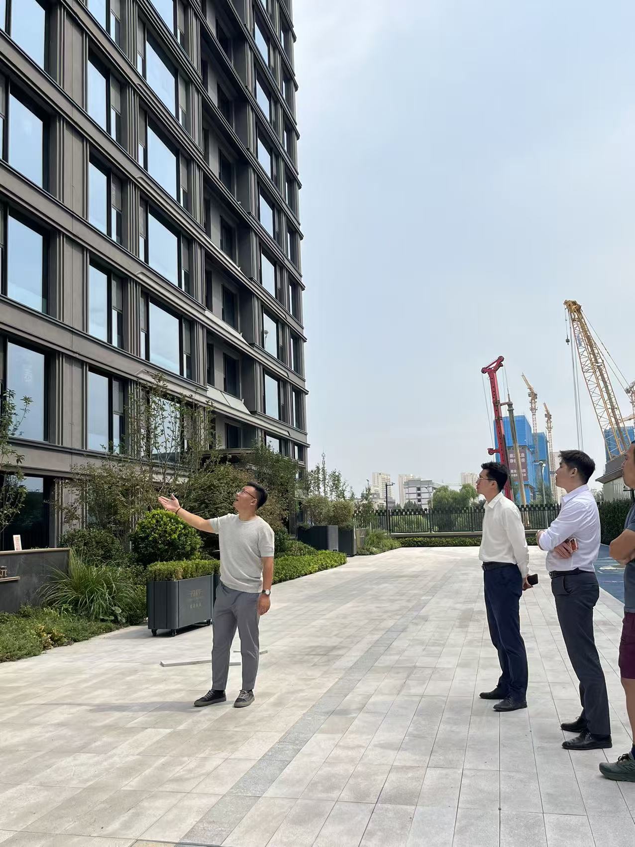 A designer explaining a building façade and its surroundings to project team members on site.